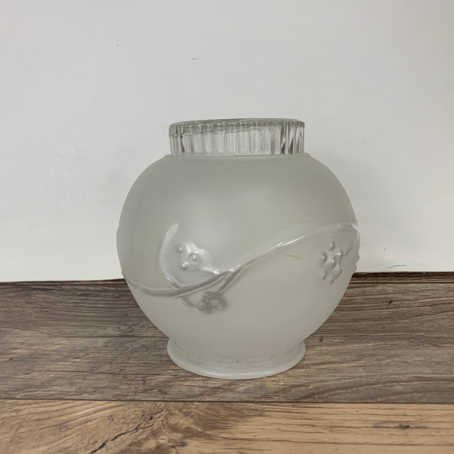 A frosted glass light cover with a raised floral accent
