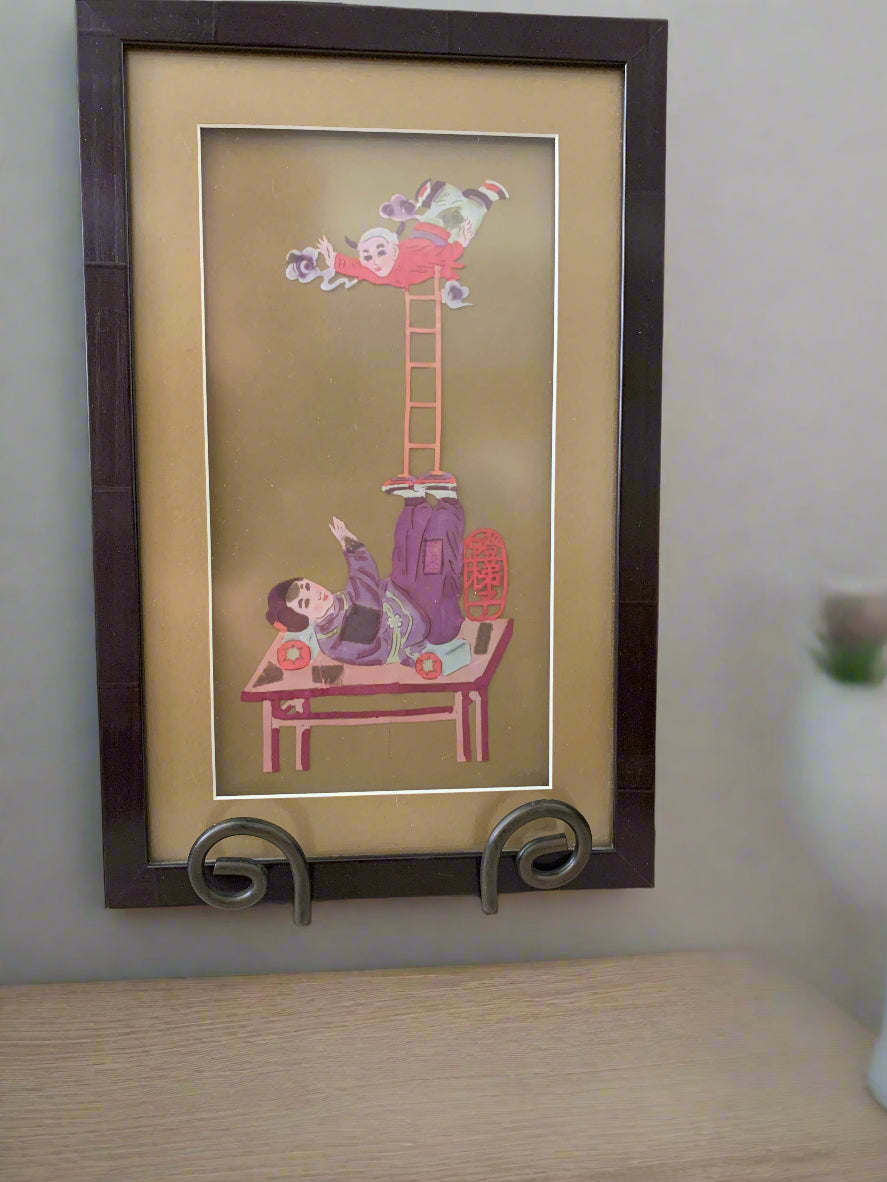 Framed artwork of two acrobats tumbling