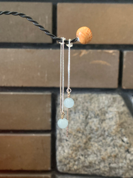 A pair of threader earrings on a hook. 