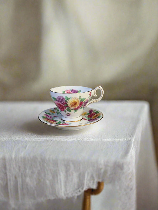 Teacup and saucer set with pink, yellow, and purple flowers on a table