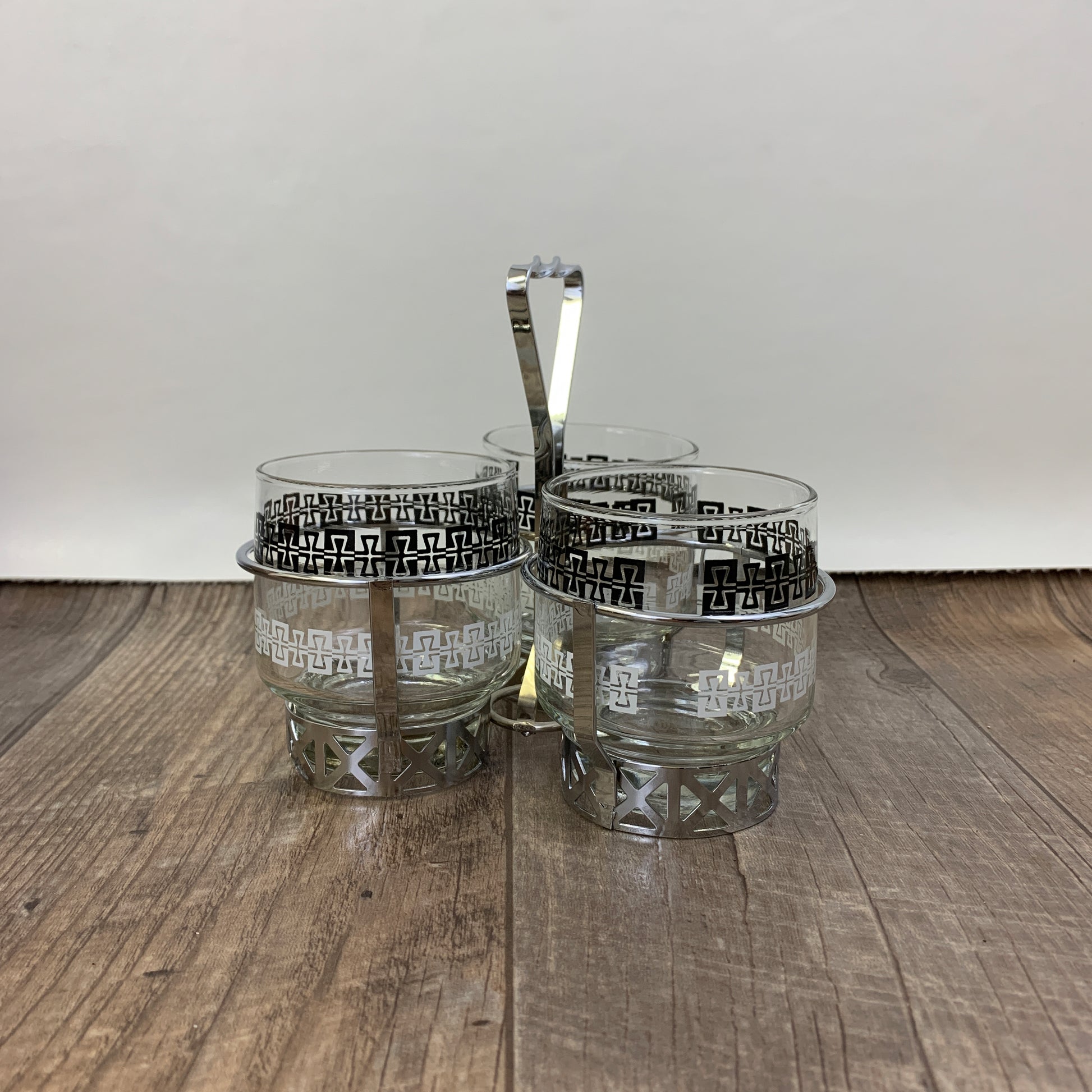 Three cups with black and white design and a silver metal holder