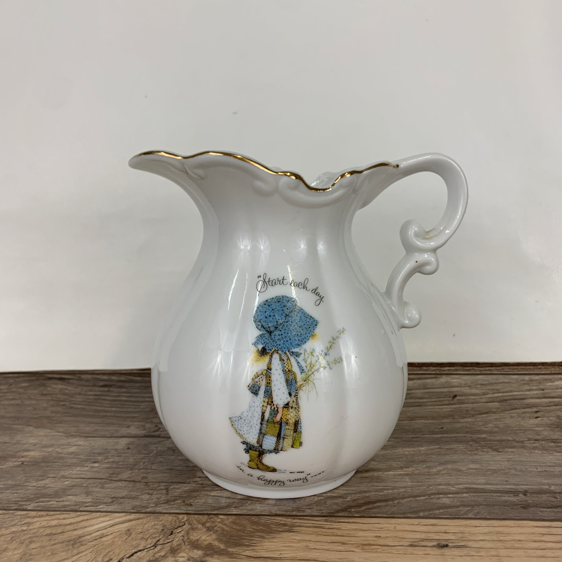 A white ceramic pitcher with Holly Hobbie on the front
