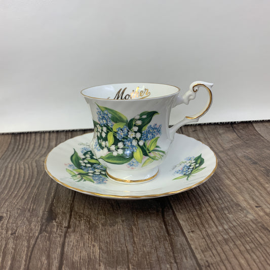 A white tea cup decorated with sprigs o Lily of the Valleys and Forget-me-nots