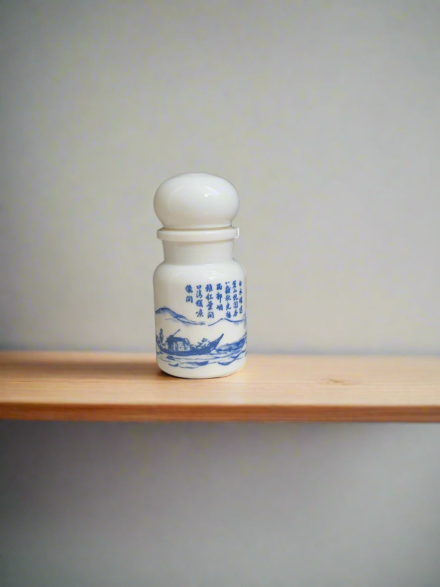 A milk glass jar with an Asian Landscape scene in blue