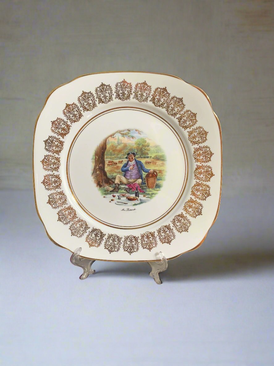 A square shaped china plate with a centre image of Mr. Pickwick having a picnic.