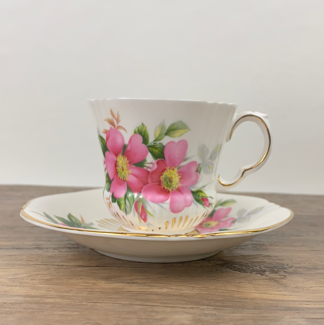 White teacup trimmed in gold decorated with pink wild roses