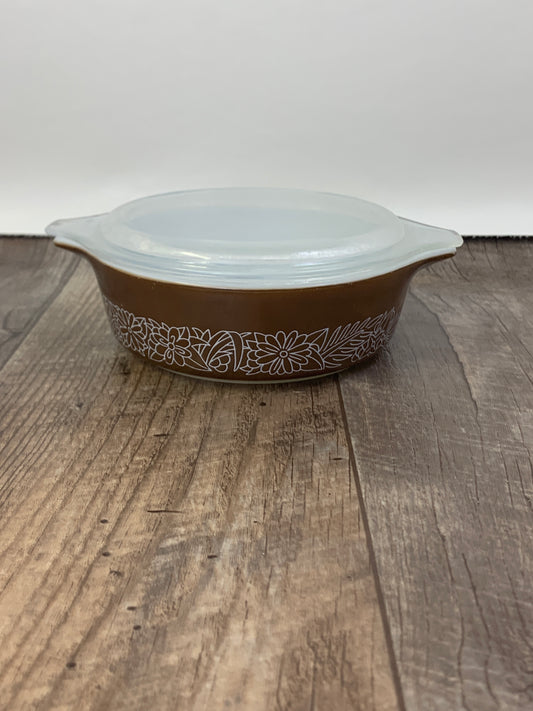 A small casserole dish with a clear lid. The dish is brown with a white outline floral pattern.