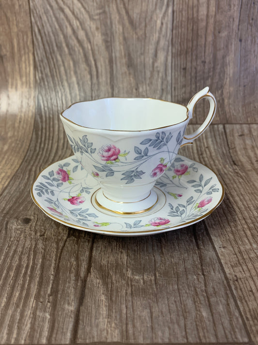A white teacup with a grey and pink floral pattern