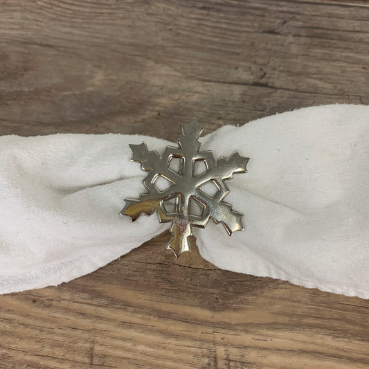 A snowflake shaped napkin ring with a white napkin