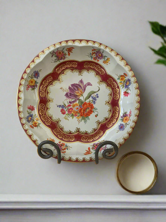Decorative plate with floral design on a stand against a white background